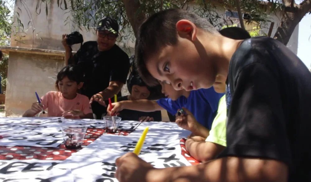 Niñas y niños pintando a brocha los letreros de PEEX.